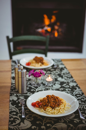 Plates of spaghetti on table next to fireplaceの写真素材
