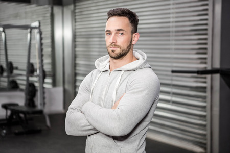 Confident man standing with arms crossed at the crossfit studioの写真素材