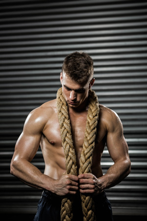 Shirtless man with battle rope around neck at the crossfit gymの写真素材