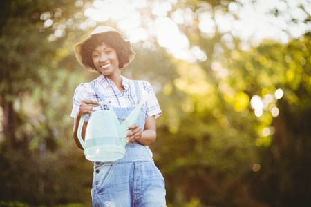 Smiling woman watering plants in the garden