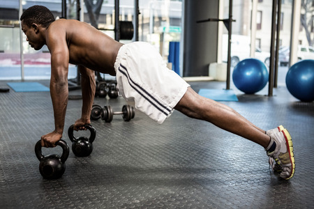 Muscular man doing push up with kettlebells at the crossfit gym