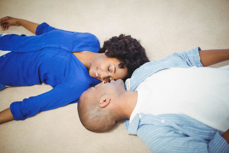 Peaceful couple lying on the floor face to faceの写真素材