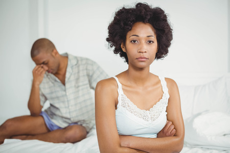 Upset woman sitting on bed after arguing with her boyfriendの写真素材