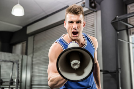 Muscular trainer shouting on megaphone at the crossfit gymの写真素材