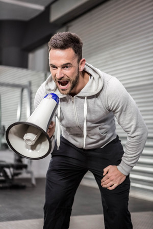 Muscular man shouting on megaphone at the crossfit gymの写真素材