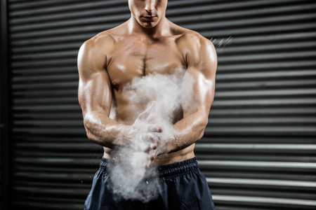 Shirtless man clapping hands with talc at the crossfit gymの写真素材