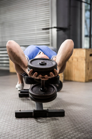 Muscular man on bench lifting dumbbell at the crossfit gymの写真素材