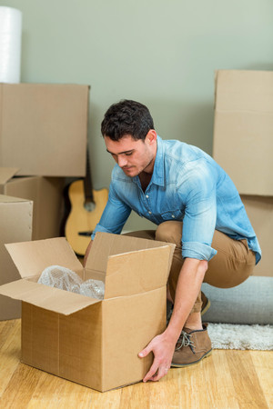 Young man carrying carton boxes in his new house houseの写真素材