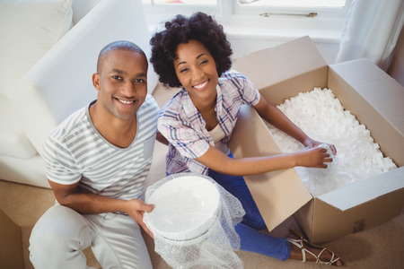Happy couple opening boxes in the living roomの写真素材