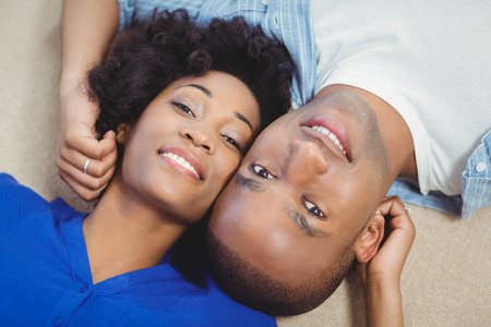 Portrait of smiling couple lying on the floor and looking at the cameraの写真素材