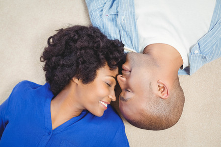 Peaceful couple lying on the floor face to faceの写真素材