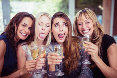 Portrait of beautiful women making funny faces and having drinks at partyの写真素材