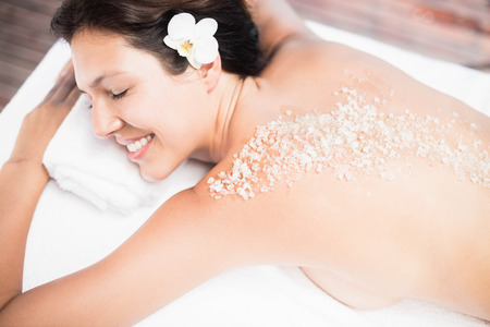 Woman lying on massage table with salt scrub on back in a spaの写真素材