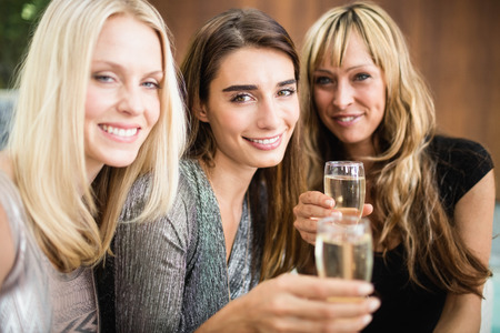 Portrait of beautiful women smiling and having drinks at the partyの写真素材
