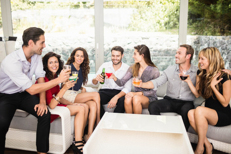 Group of friends talking to each other and cocktail drinks at partyの写真素材