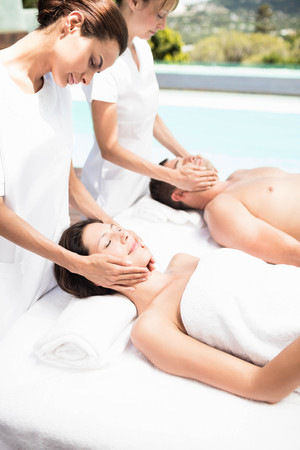 Couple receiving a face massage from masseur in spaの写真素材