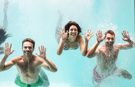 Two couples enjoying and swimming underwater in swimming pool