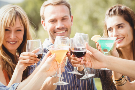 Happy young friends having drinks at swimming pool and enjoying holiday