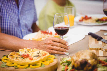 Senior man holding a glass of wine on dining table