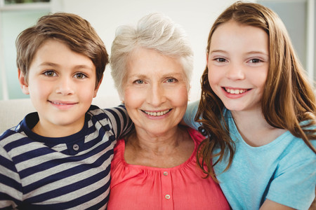 Portrait of grandmother and grandchildren sitting together on sofa in living room