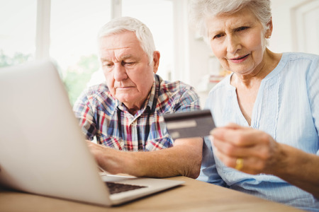 Senior couple paying bills online on laptopの写真素材