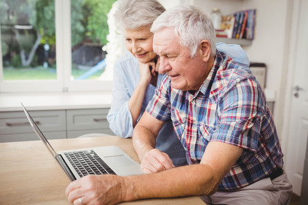 Senior couple using laptop at homeの写真素材
