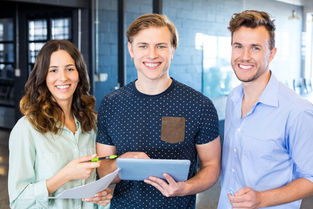 Three confident colleagues discussing in office with documents and tablet