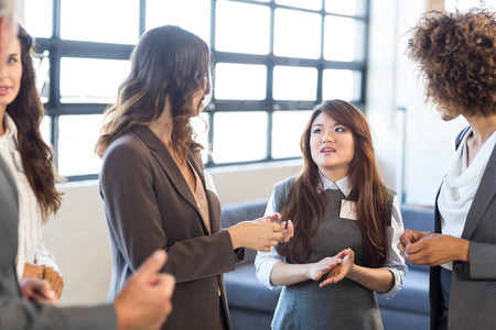 Business team standing together and interacting in officeの写真素材