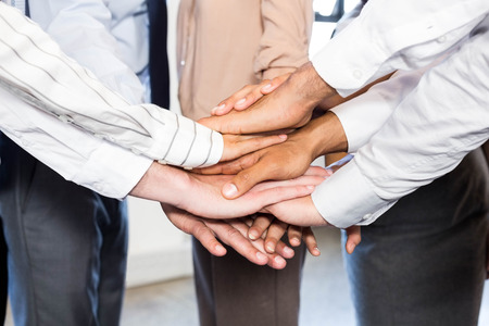 Close-up of businesspeople stacking hands in office