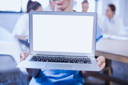 Close-up of female doctor showing laptop and other doctors discussing behind in conference roomの写真素材