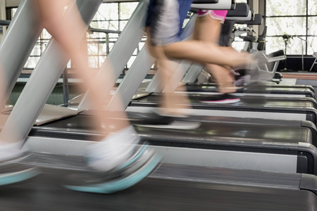 Women and men running on a treadmill at the gymの写真素材