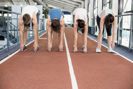 Four athletic women and men stretching on running trackの写真素材