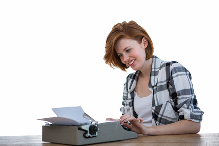 smiling hipster woman sitting at a desk, typing on her typewriterの写真素材