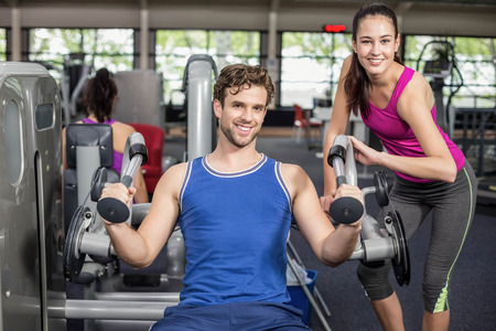 Trainer woman helping athletic man in gym