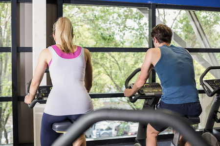 Fit people doing exercise bike at gym