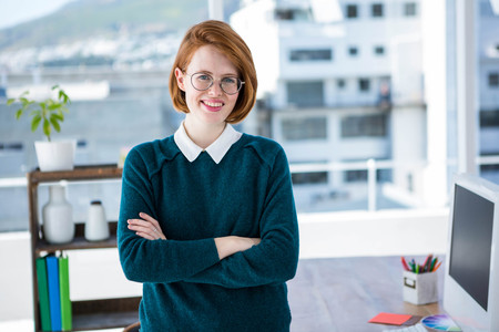 smiling hipster business woman, standing in her office with her arms foldedの写真素材