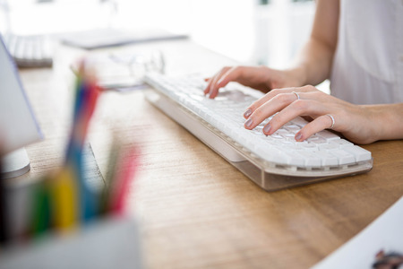 womans hands typing on a keyboard in an office