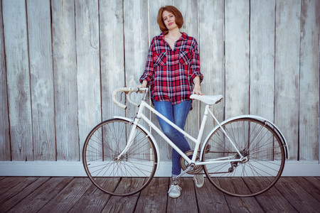 beautiful hipster woman with a bicycle, standing against a wooden backgroundの写真素材