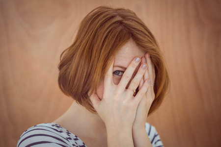beautiful hipster woman hiding her face on a wooden backgroundの写真素材