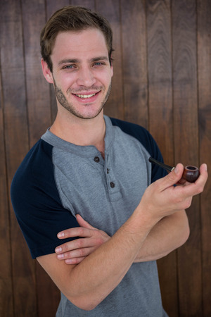 Handsome hipster smoking pipe on wooden backgroundの写真素材
