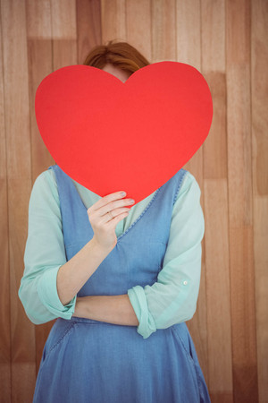 Pretty hipster holding heart on wooden backgroundの写真素材