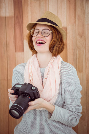 Hipster smiling and holding camera on wooden backgroundの写真素材