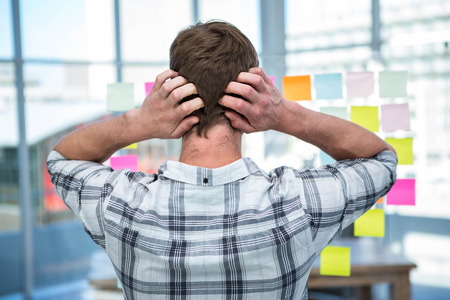 Worried hipster man in front of post-it in officeの写真素材