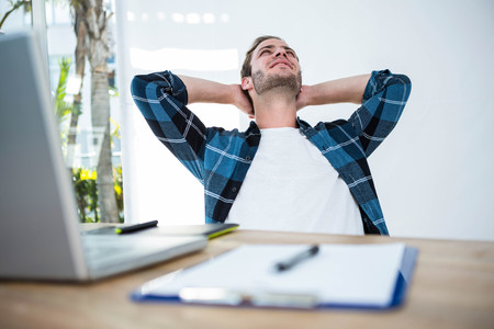 Handsome man relaxing on his desk chair in a bright officeの写真素材