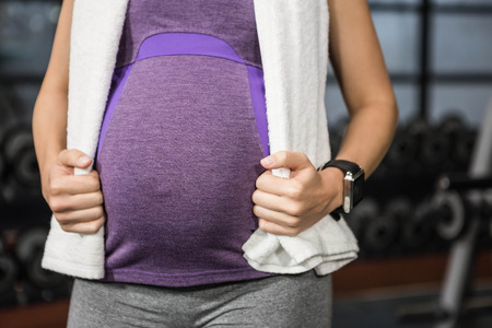 Mid section of pregnant woman standing at the gym
