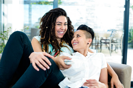Lesbian couple relaxing on sofa and watching televisionの写真素材
