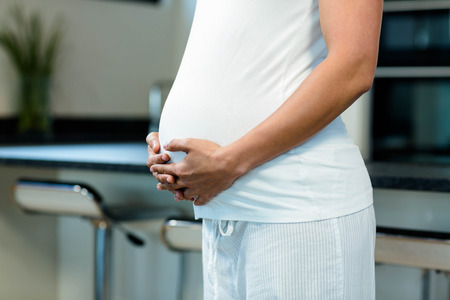 Mid section of pregnant woman touching her bellyの写真素材