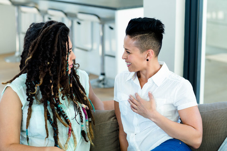 Lesbian couple talking to each other in living roomの写真素材