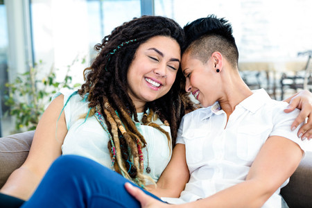 Happy lesbian couple relaxing on sofa in living roomの写真素材