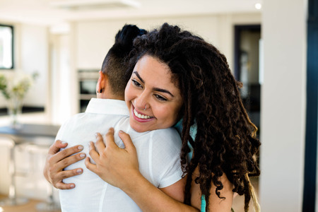 Lesbian couple embracing each other in living roomの写真素材